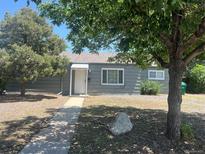 A charming single-story home with a gray exterior, surrounded by mature trees and a sidewalk leading to the entrance at 772 Victor St, Aurora, CO 80011