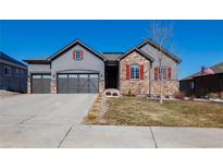Charming two-story home featuring a three-car garage, stone accents, and manicured lawn in a residential neighborhood at 3790 Mighty Oaks St, Castle Rock, CO 80104
