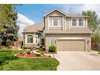 Charming two-story home with stone accents, manicured lawn, and attached two car garage at 1210 Snowberry Ln, Broomfield, CO 80020