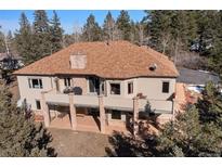 Two-story house with a large balcony, brick supports, mature trees and a brown shingle roof at 21016 Horse Bit Way, Morrison, CO 80465