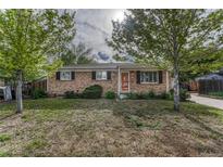 Charming single-story brick home with lush front yard and mature trees in a quiet neighborhood setting at 11957 Claude Ct, Northglenn, CO 80233