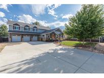 Spacious home featuring an extra wide driveway, three-car garage, well-kept lawn, and charming front porch at 10640 W 46Th Ave, Wheat Ridge, CO 80033