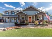 Inviting two-story home showcasing a charming front porch, green lawn, and a colorful orange front door at 10640 W 46Th Ave, Wheat Ridge, CO 80033