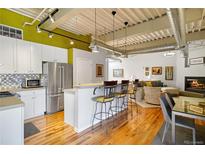 Open kitchen features island with seating, stainless steel appliances, and wood floors at 1435 Wazee St # 504, Denver, CO 80202