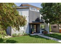 Modern two-story home with gray stucco and black metal accents, complemented by a lush green lawn and mature trees at 2048 Meade St, Denver, CO 80211