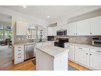 Bright kitchen with white cabinets, stainless steel appliances, kitchen island and tile backsplash at 604 S Yarrow St, Lakewood, CO 80226