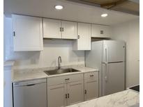 Well-lit kitchen featuring white cabinetry, stainless steel sink, and marble countertops at 943 S Zeno Way # 205, Aurora, CO 80017
