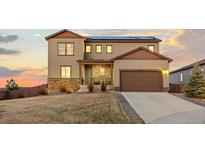 Beautiful two-story home with a manicured lawn, a two-car garage, and solar panels on the roof at sunset at 3234 Picketwire Way, Castle Rock, CO 80108