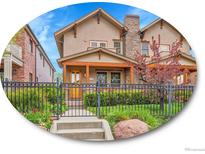 Charming two-story home featuring a stone chimney and a welcoming front porch with wood columns and decorative fence at 383 S Franklin St, Denver, CO 80209