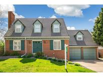 Charming brick home featuring a lush front lawn, dormer windows, and an attached two-car garage at 7193 S Newport Way, Centennial, CO 80112