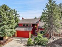 Charming two-story home with a red garage door, mature trees, and landscaped front yard at 15740 Sandtrap Way, Morrison, CO 80465