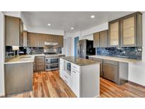 This kitchen features stainless steel appliances, light countertops, wooden floors, and a center island at 15740 Sandtrap Way, Morrison, CO 80465