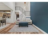 Bright living room features modern staircase, blue accent wall, and open-concept layout with stylish furniture at 14252 E Radcliff Cir, Aurora, CO 80015