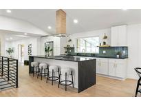 Modern kitchen boasts a spacious island, stainless steel appliances, and sleek white cabinetry at 7382 W Stanford Ave, Littleton, CO 80123