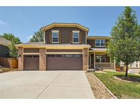 Two-story house with a brown exterior, three-car garage, and well-maintained lawn at 1546 Hickory Dr, Erie, CO 80516