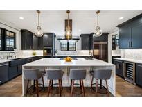 Modern kitchen with white countertops, black cabinetry, stainless appliances, and pendant lighting over a large island at 2732 S Jackson St, Denver, CO 80210