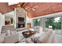 Inviting living room with stone fireplace, wood ceiling, ceiling fan and sliding glass doors to outside deck at 23485 Bluestem Dr, Golden, CO 80401