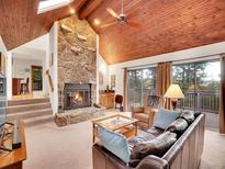 Inviting living room with a stone fireplace and wood-paneled vaulted ceiling, perfect for cozy evenings at 23485 Bluestem Dr, Golden, CO 80401