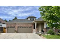 Charming brick home with a three-car garage and covered porch, nestled in a green, landscaped neighborhood at 1762 Granger Cir, Castle Rock, CO 80109