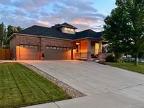 Charming brick home featuring a large driveway, attached three-car garage, and welcoming covered front porch at 1762 Granger Cir, Castle Rock, CO 80109