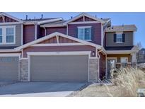 Inviting two-story townhome featuring a two-car garage, stone accents, and fresh landscaping at 5683 Raleigh Cir, Castle Rock, CO 80104