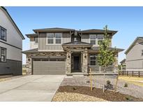 Charming two-story home with a landscaped front yard, stone accents, covered porch, and a two-car garage at 10727 Snowdon St, Parker, CO 80134