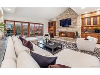 Inviting living room with stone fireplace, custom cabinets and a large window with natural light at 62 N Ranch Rd, Littleton, CO 80127