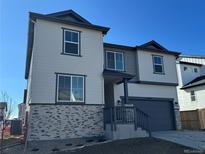 Beautiful two-story home boasts modern design, gray siding and stone accents, and well-manicured front yard at 2025 Barnwood Dr, Brighton, CO 80601