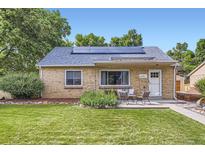 Charming brick home featuring solar panels, manicured lawn, and inviting front patio seating area at 6995 W 27Th Ave, Wheat Ridge, CO 80033