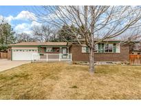 Charming brick home featuring a well-manicured lawn and a welcoming white picket fence at 10723 Sperry St, Northglenn, CO 80234