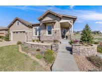 Charming single-Gathering home featuring a stone-accented facade, landscaped front yard, and inviting entryway with a covered porch at 360 Basilwood Way, Highlands Ranch, CO 80126