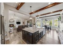 Open concept kitchen with a large center island, wooden beams, and stainless steel appliances at 360 Basilwood Way, Highlands Ranch, CO 80126