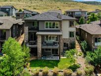 Beautiful three-story home featuring stone accents, balconies, and a well-maintained landscaped yard at 9395 Night Star Pl, Lone Tree, CO 80124