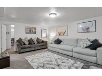 A cozy living room featuring two sofas, decorative pillows, and eye-catching highland cow art at 61 S 17Th Ave Dr, Brighton, CO 80601