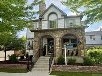Charming two-story home showcasing a stone facade, arched entryway, and beautifully landscaped front yard at 3357 N Akron Ct, Denver, CO 80238