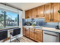 Modern kitchen features a large window with seating, wooden cabinets, and updated appliances at 3224 Troy St, Aurora, CO 80011