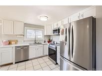 Bright kitchen with white cabinets, stainless steel appliances, and tile flooring at 4354 Chase St, Denver, CO 80212