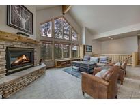 Inviting living room with stone fireplace and large windows showcasing natural light and beautiful outdoor views at 89 Fairview Cir, Breckenridge, CO 80424