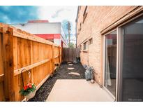 Private backyard area features a wooden fence, mulch, concrete patio, and sliding glass door access to the building's interior at 558 N Washington St # 103, Denver, CO 80203
