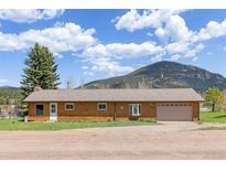 Charming single-story home with attached garage, wood facade, and mountain backdrop at 26063 Morris Ave, Conifer, CO 80433