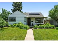 Charming home with a well-manicured front yard, complemented by lush greenery and solar panels at 1240 Ulster St, Denver, CO 80220