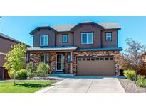 Inviting two-story home featuring a two-car garage, manicured lawn, and stylish stone and siding accents at 25046 E Bayaud Pl, Aurora, CO 80018