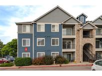 Exterior of blue apartment building with balconies, a brick facade staircase, and car parking at 4451 S Ammons St # 2-204, Littleton, CO 80123