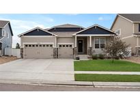 Charming home with a three-car garage, well-maintained lawn, and stone column accents at 2200 Cadman St, Berthoud, CO 80513