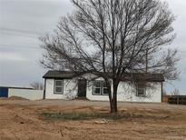 Newly remodeled single Gathering house with fresh white paint, black trim and a mature tree in front at 7486 Harold St, Fort Lupton, CO 80621