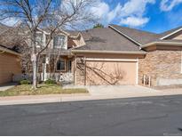 Charming exterior featuring a two-car garage, brick accents, and mature trees. A welcoming suburban residence at 8579 S Miller Way, Littleton, CO 80127