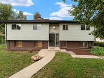 Charming two-story home with light green siding and manicured front yard and walkway leading to the front door at 1075 Dudley St, Lakewood, CO 80215
