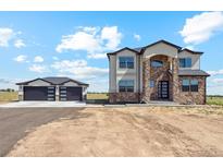 Two-story home with stone accents and a detached two-car garage at 995 Pinehurst Ct, Bennett, CO 80102