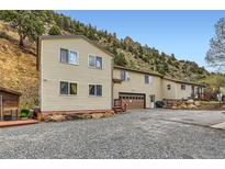 Spacious home featuring a two-car garage, gravel driveway, and a hillside backdrop at 4 Virginia St, Idaho Springs, CO 80452