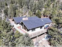 An aerial view of a beautiful two-story home with a large deck surrounded by lush trees and mountain landscape at 2218 Witter Gulch Rd, Evergreen, CO 80439